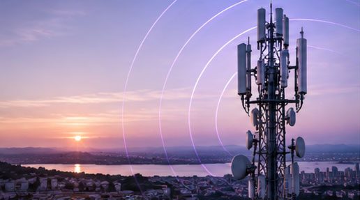A mobile network mast broadcasting over a city at sunset